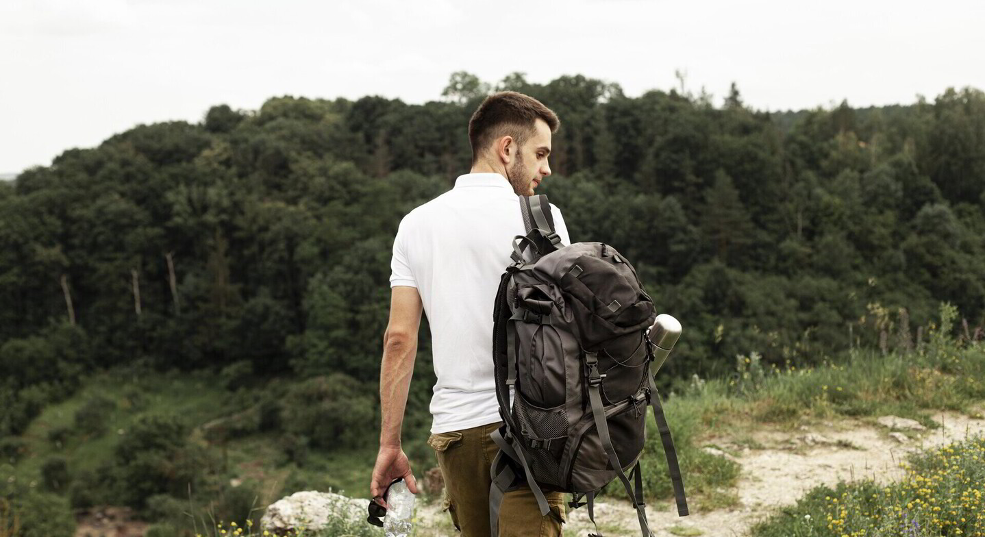 Man carrying a backpack while walking on a forest trail